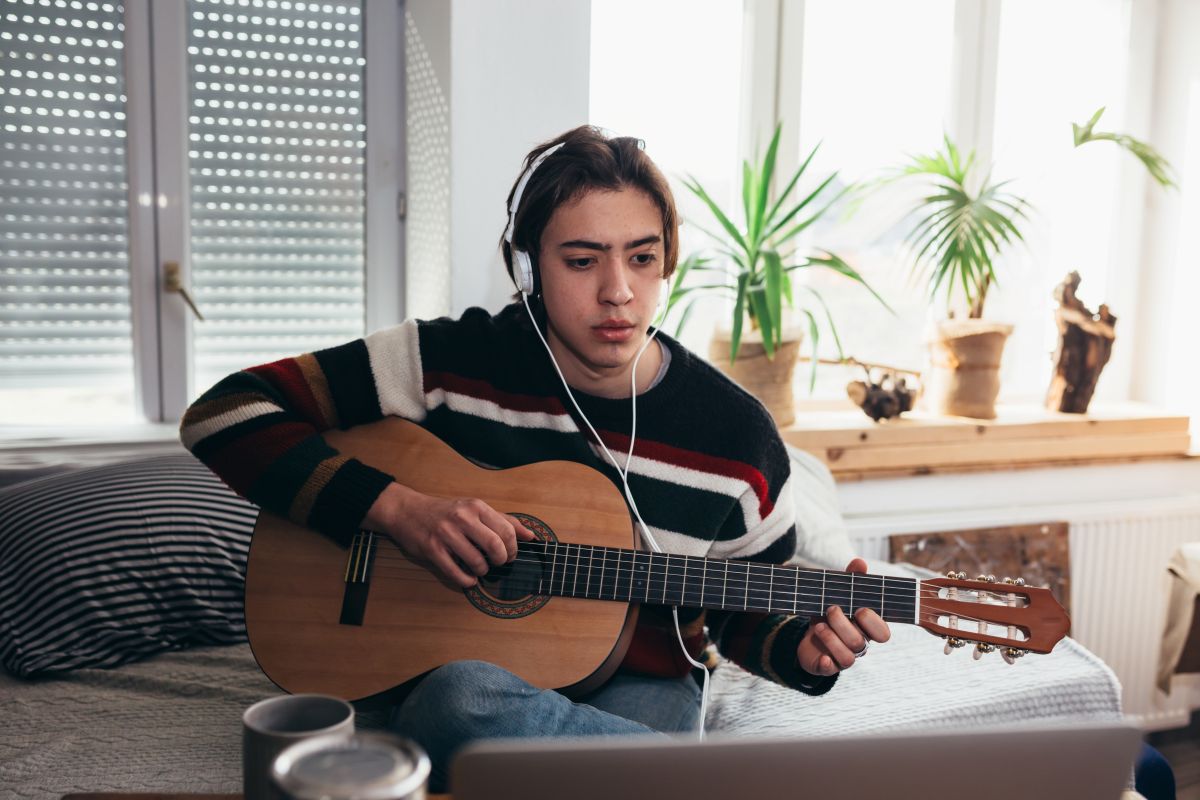 A woman with an laptop in front of her taking online guitar lessons